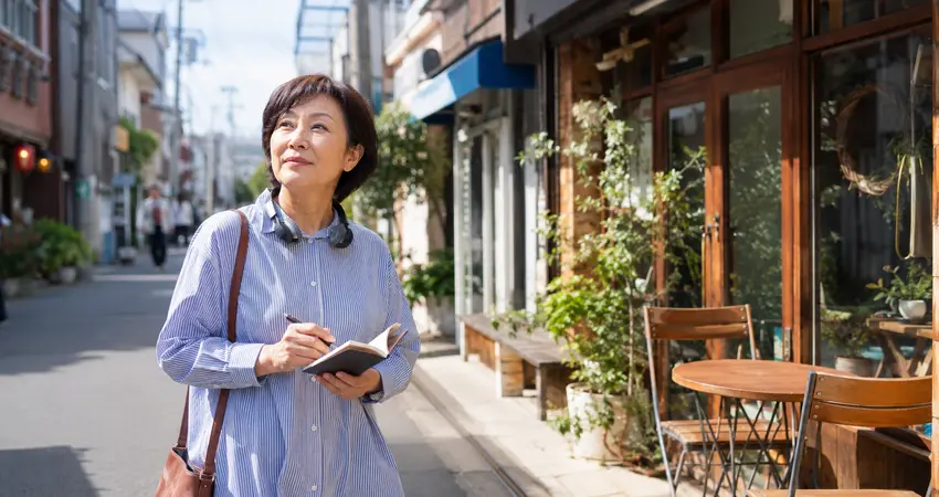 街を歩きながらラジオ番組の話題をメモする50代の女性